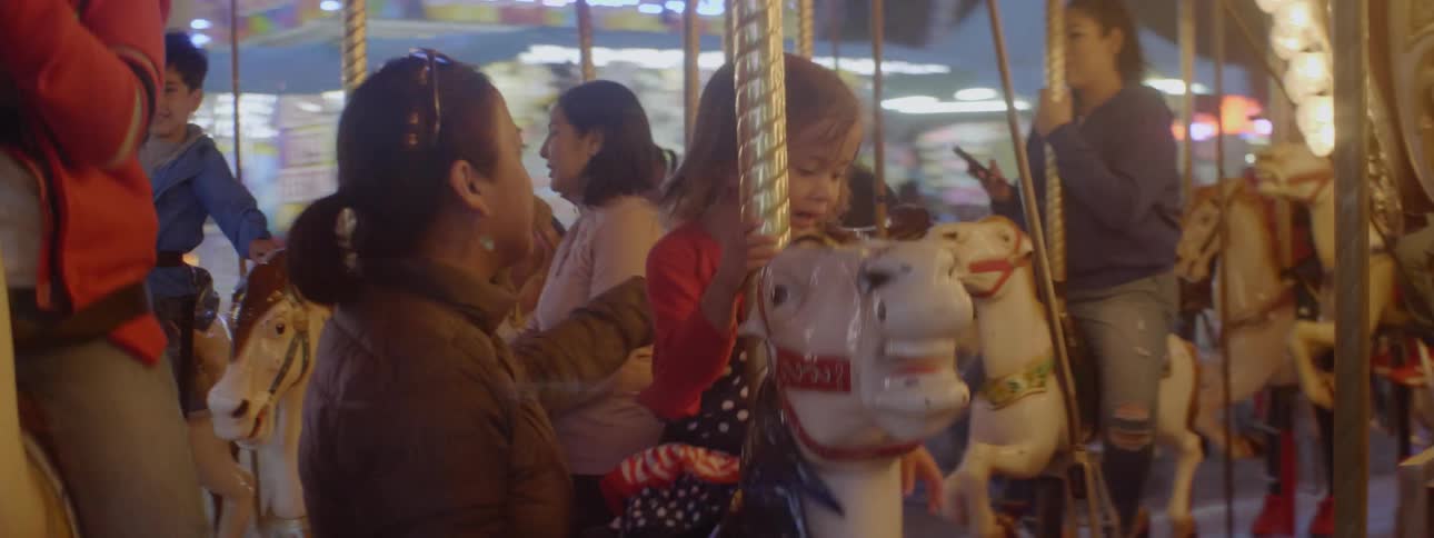 People smile while riding on a carousel at night