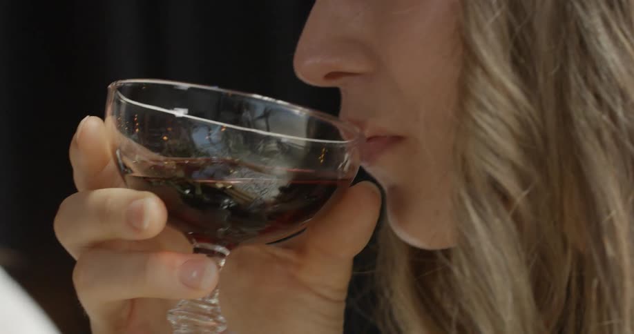 A woman sips wine from a glass