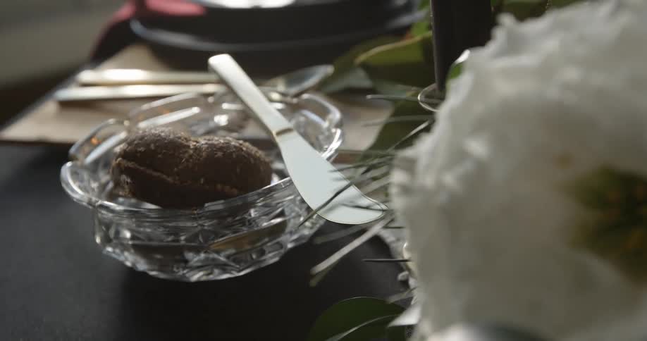 A floral centerpiece sits beside a glass bowl and butter knife