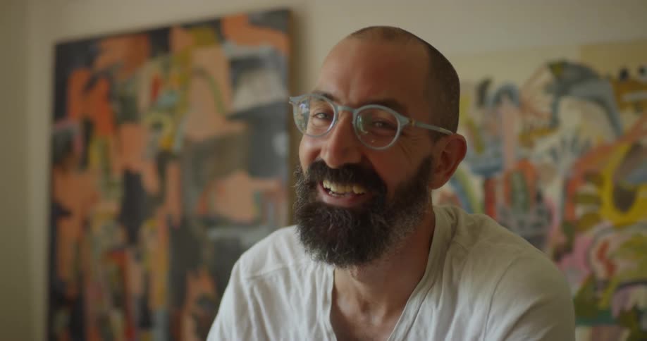 The man laughs near the paintings