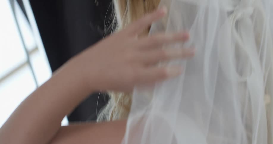 A blonde woman wearing a wedding dress moves her arms around