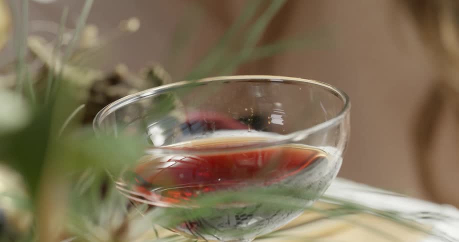 A clear glass filled on a table with a plant next to it