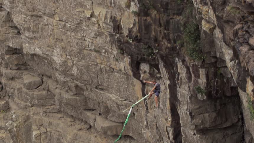 A man bungee jumps off a cliff into the valley below