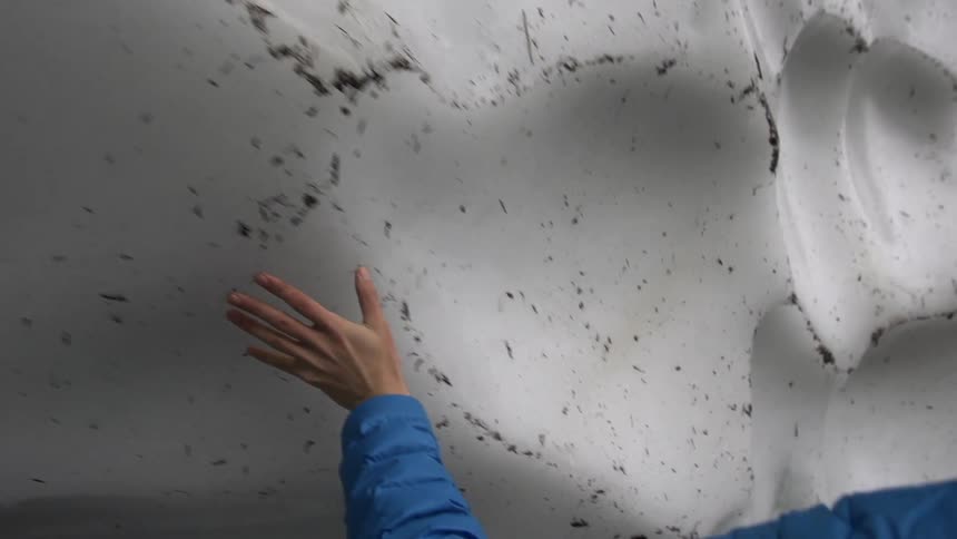 A man moves his hand along a ice wall
