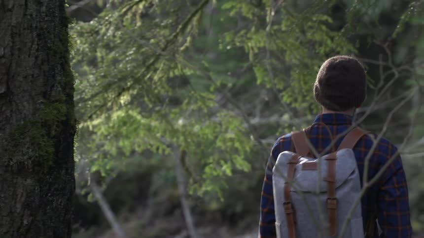A man wearing a backpack walks over to a river