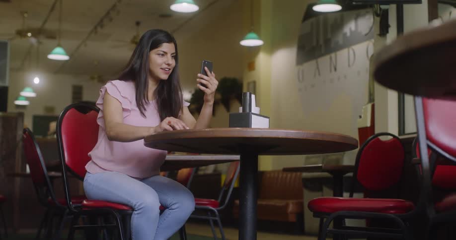 A woman makes a video call inside a restaurant