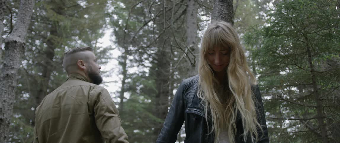 The man and woman hold hands in the woods