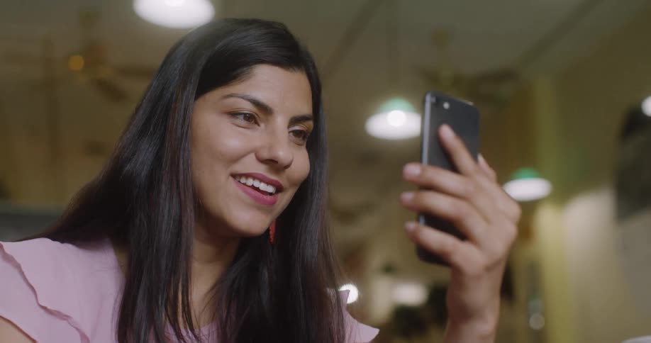 Woman smiles as she holds her cellphone and talks to it