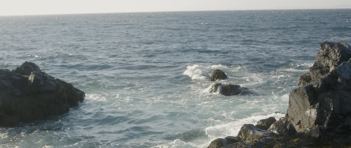 The beach has rough waves splashing against the shore