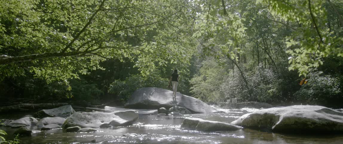 Woman climbing a riverbank boulder