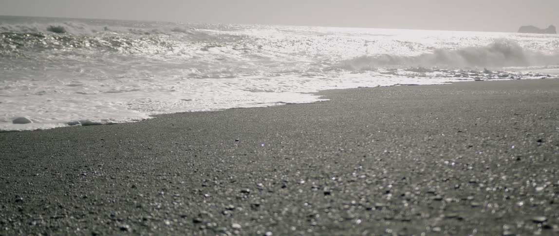 The waves slowly cover the pebbles of the shore