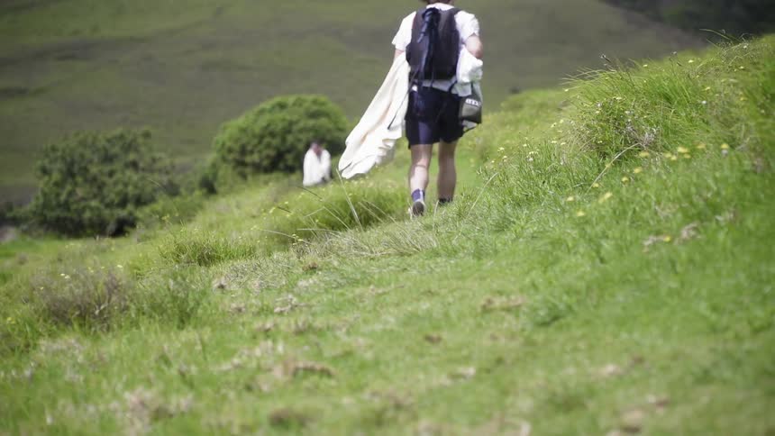 The man is hiking towards someone on the hill