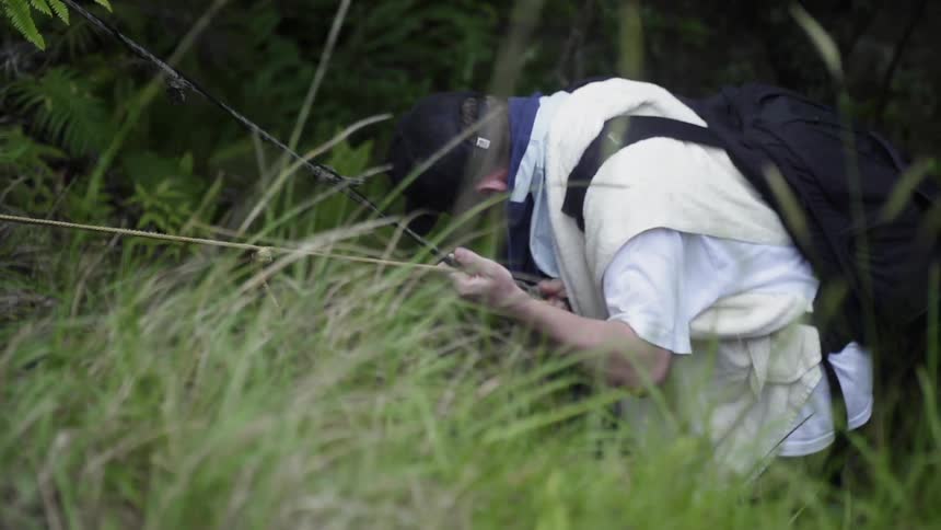 The man is climbing down the hill with ropes