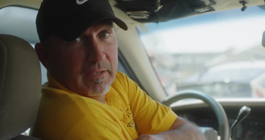 The driver looks and talks with the backseat passenger