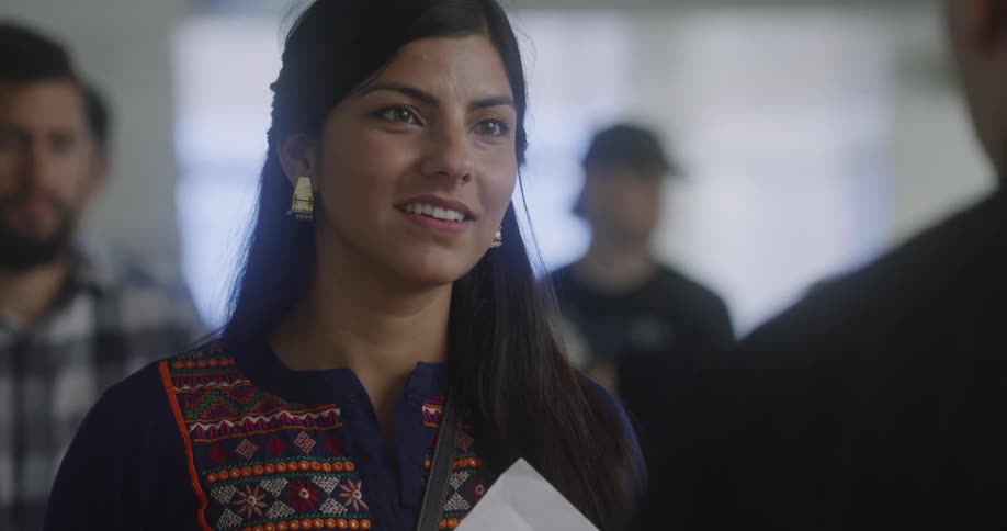 A woman talks while handing over a document to a man