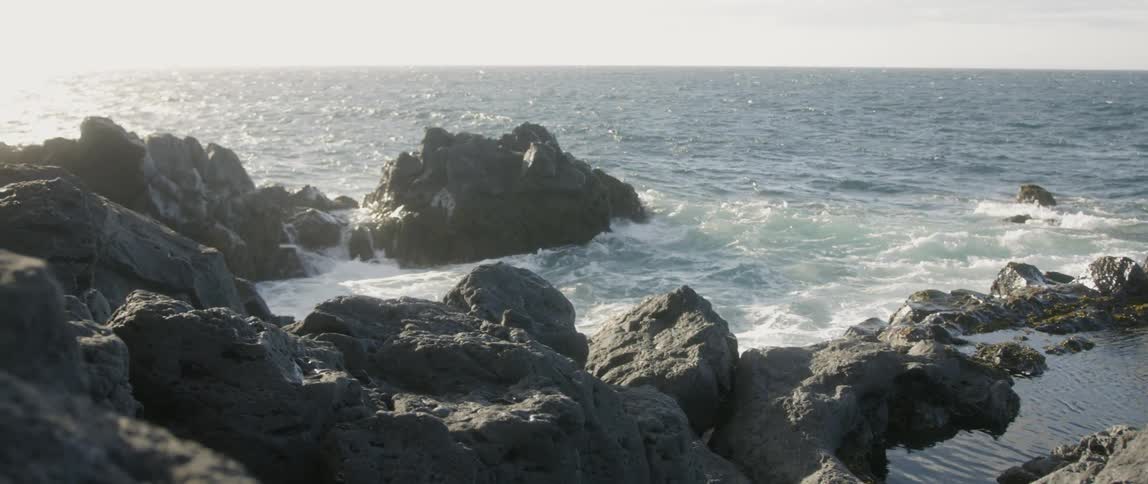 The rough waves crash against the rocks by the shore