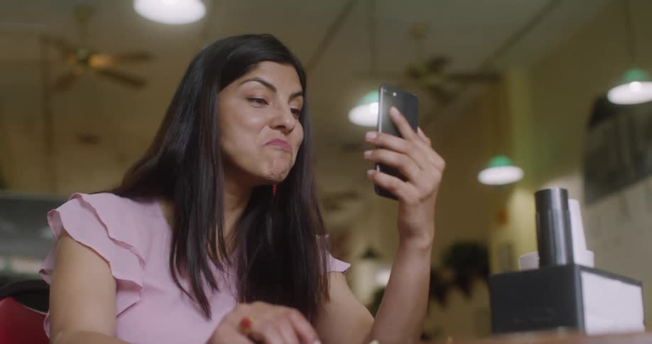 A woman has a video chat on her phone inside a restaurant
