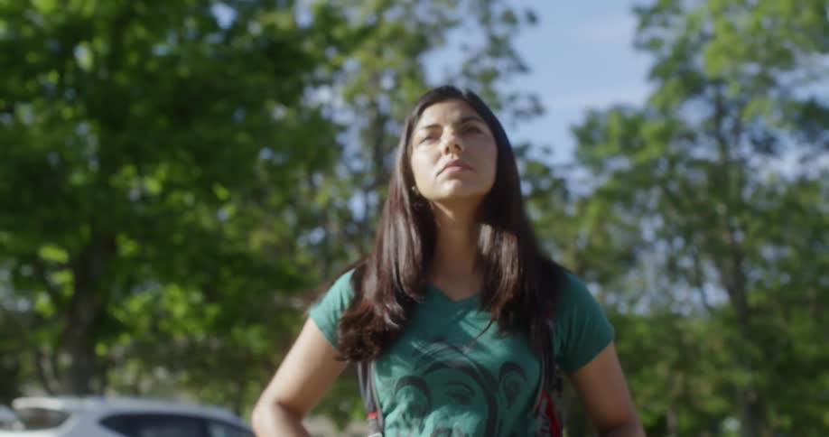 A woman walks outside with a backpack on a sunny day