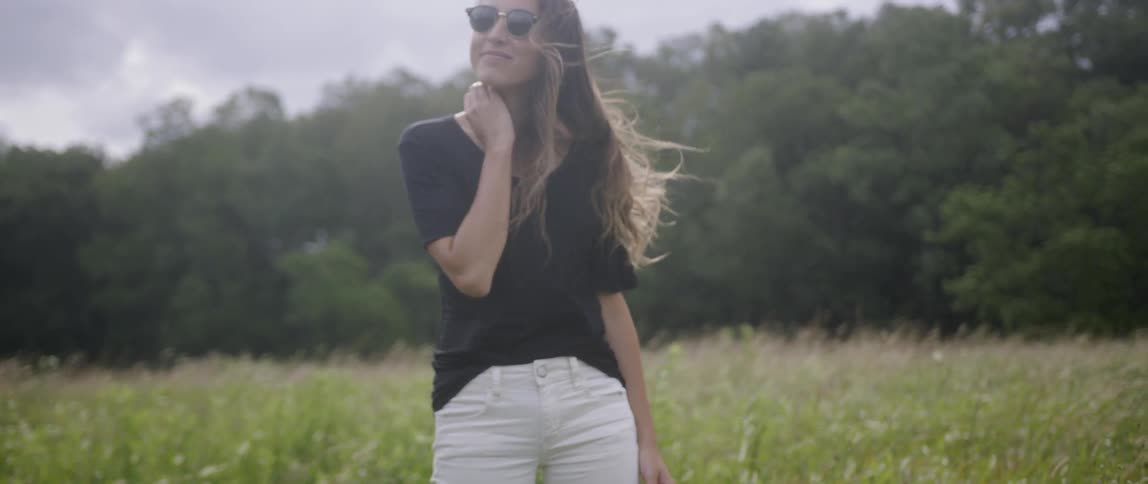 The woman stands smiling in the wind