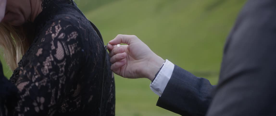 A man zips up a woman's black gown