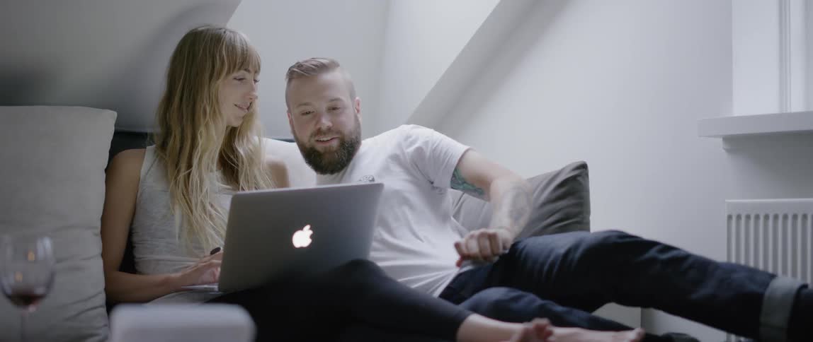 The two people lay on the bed using the laptop