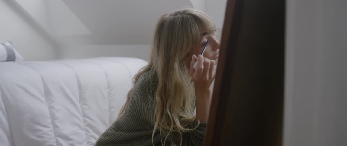 The woman is applying makeup to her eye lashes