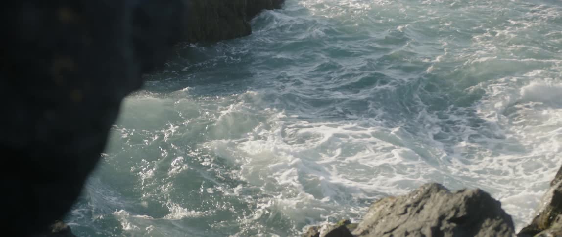 The tide flows against the rocky shore