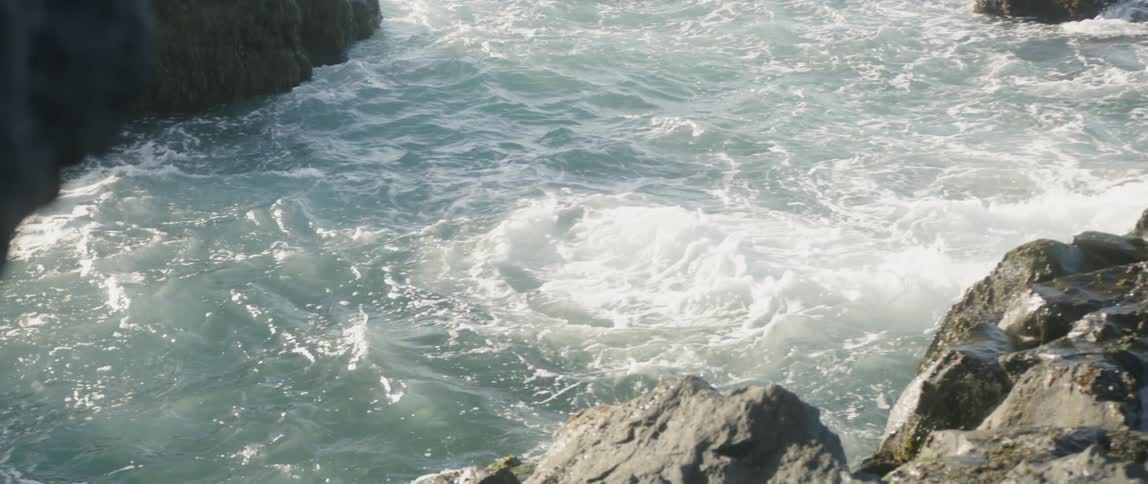 Ocean water is flowing and rippling between large rocks