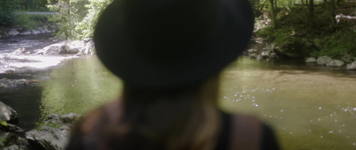 A woman looks out at the flowing river