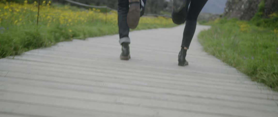 A man and woman run while holding hands