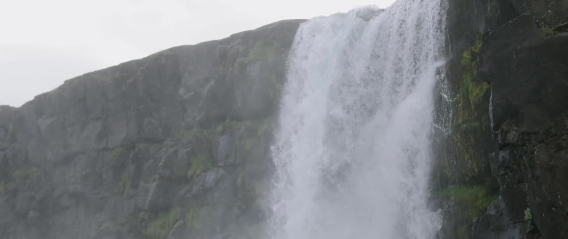 The waterfall pours off splashing on the rocks