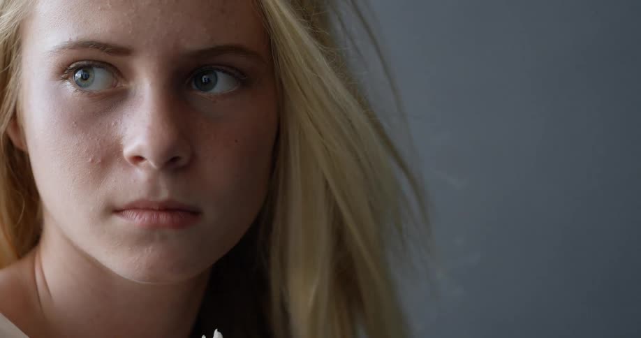 A blonde haired girl looks worried as she stares to the side