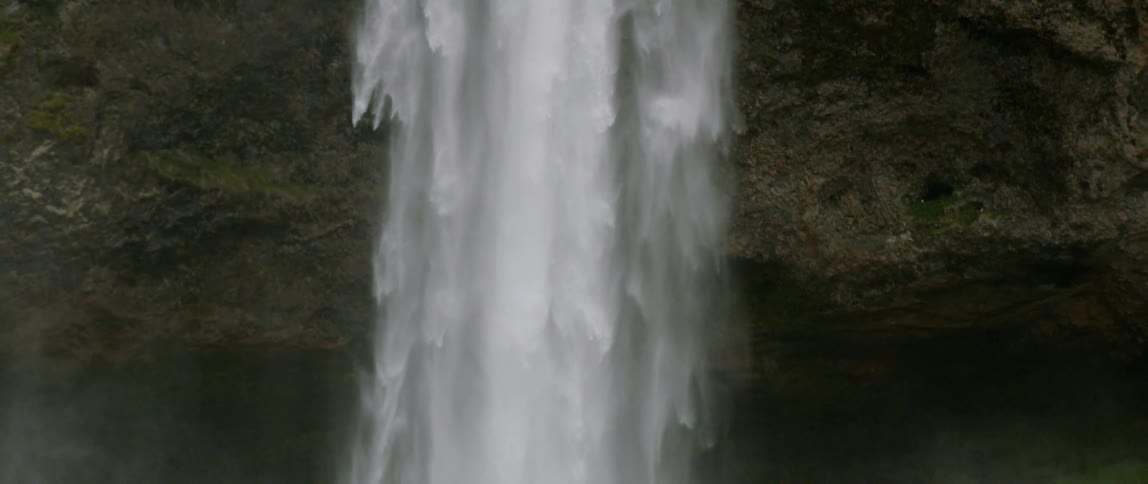 The waterfall slowly pours down into the spring