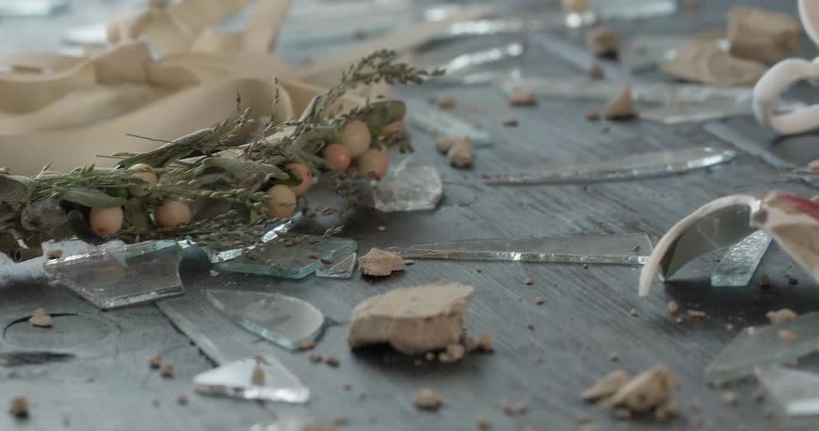 Broken pieces of pottery and glass, and a small branch with berries lay on the deck