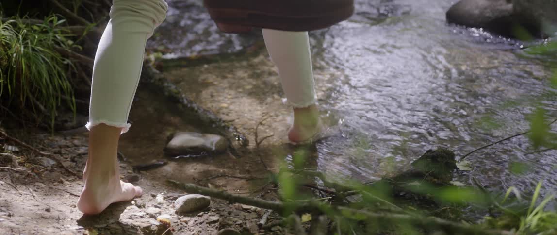 Woman walks barefoot into a stream of water