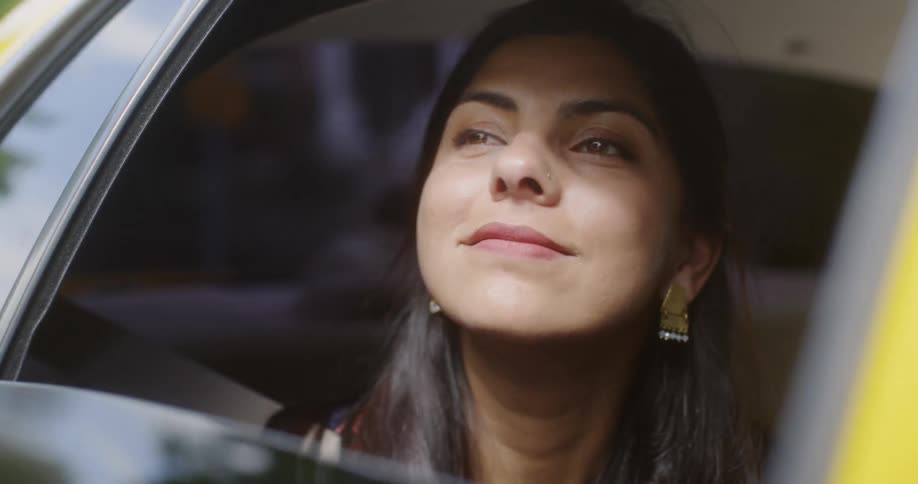 A woman smiles while riding in the backseat of a car