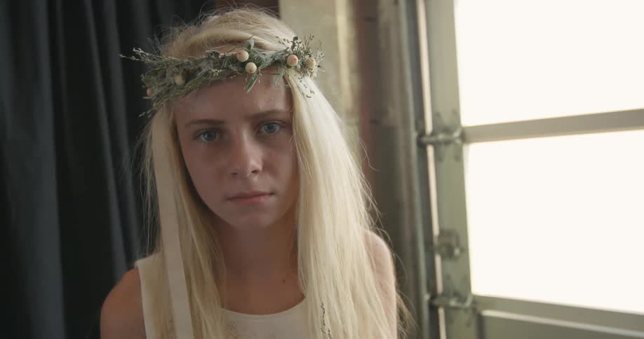 A woman wearing a grown of flowers is looking at the camera