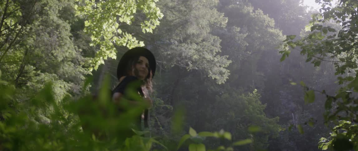 A woman carries a bag in a sunny forest