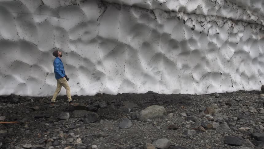 A man is walking next to a wall of ice