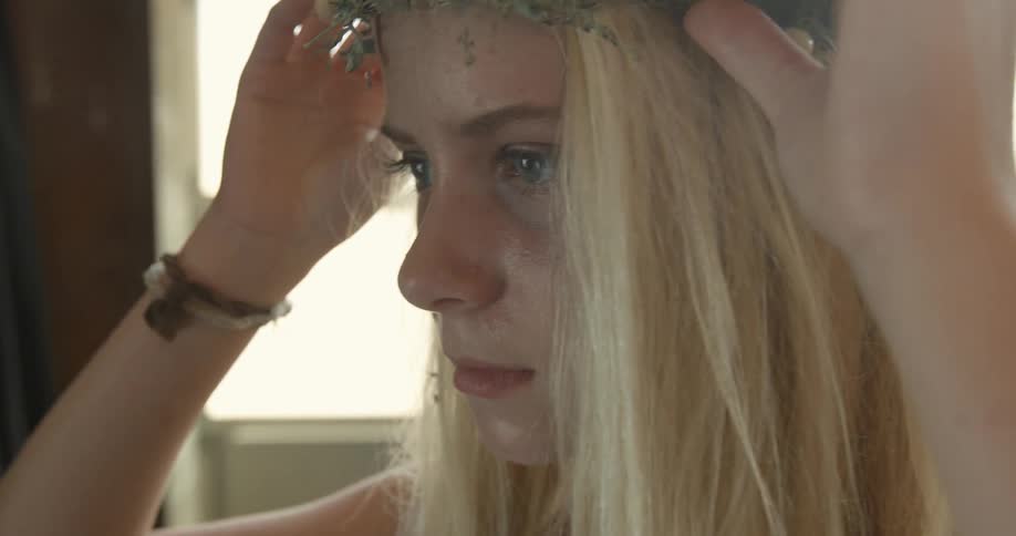 A woman is adjusting her crown of flowers
