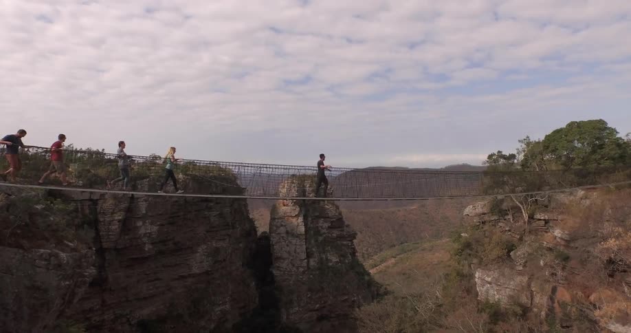 People walking over a rope bridge crossing a cavern