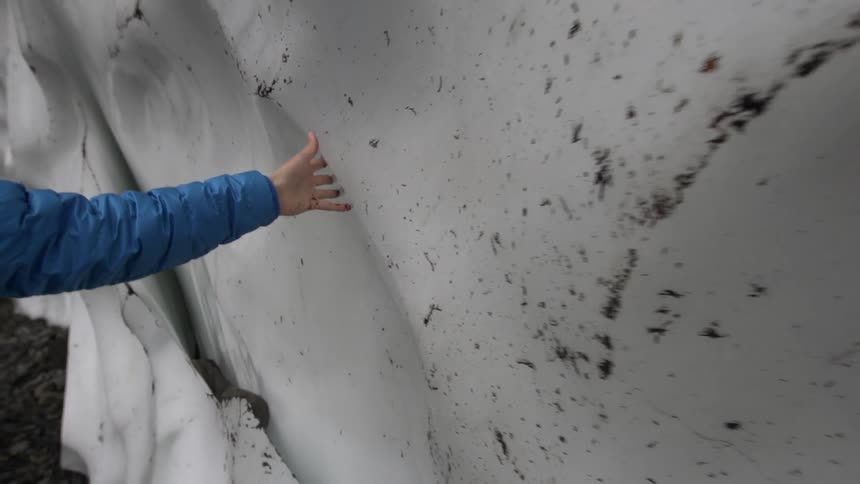 A man traces his hand along a huge ice wall