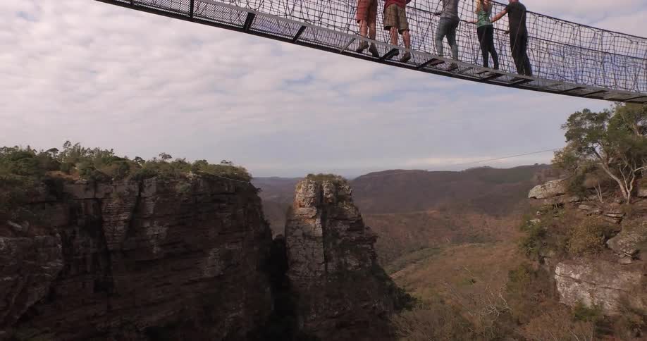 People gazing at scenery from a rope bridge over a canyon on a cloudy day