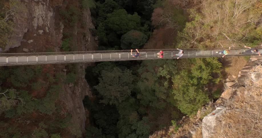 People walk across a narrow bridge