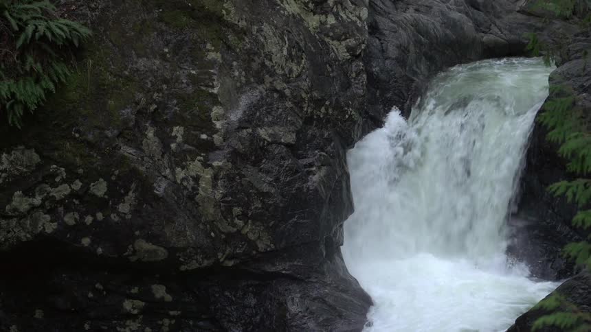 A small waterfall pours through a rift in a rocky riverbed