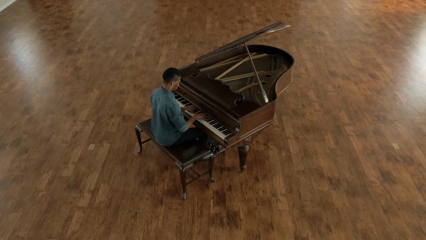 A man is sitting at a piano and playing it