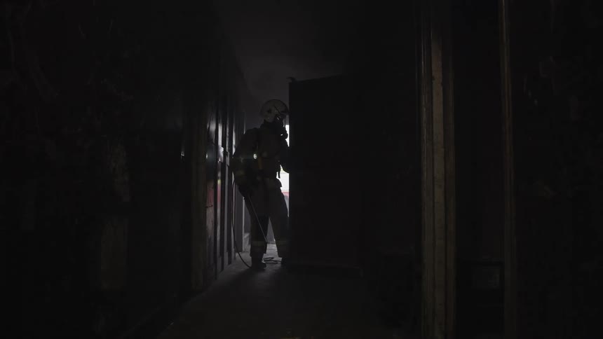 The firefighter searches the rooms in a dark home