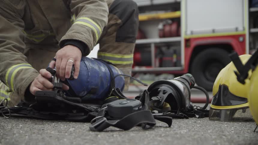 The person is attaching a canister to his gear