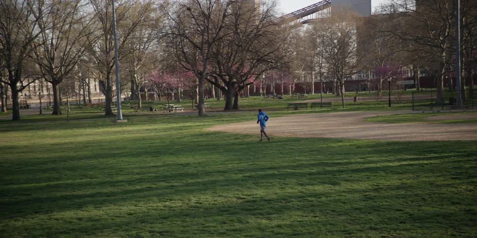 A child running across a grass field towards some trees
