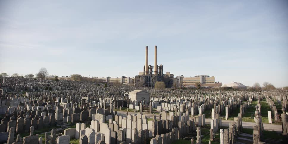 Headstones are situated in front of a factory